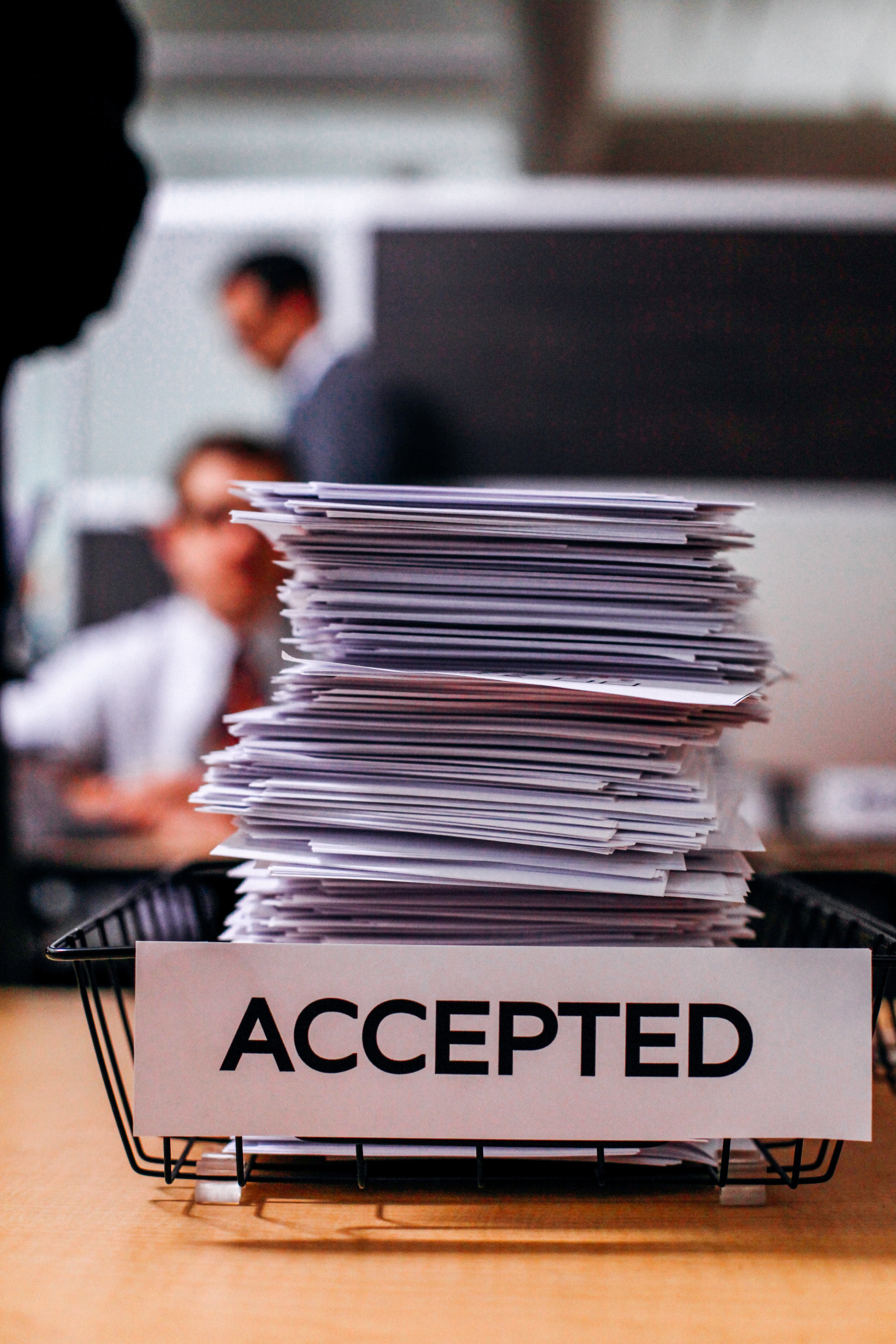 Photo of a stack of paper in a paper bin labelled "Accepted"