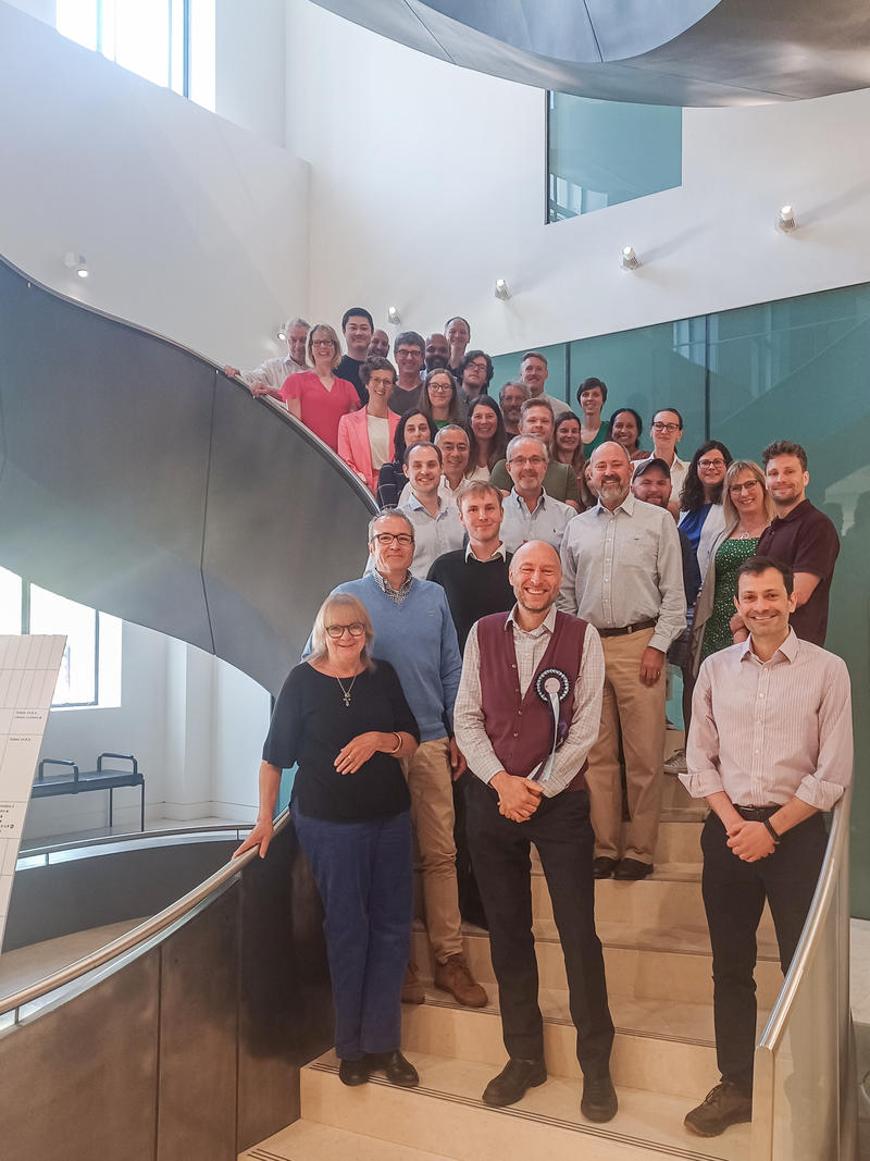 Group photo of the PAINSTORM consortium. About 25 people are standing on a large spiral staircase.