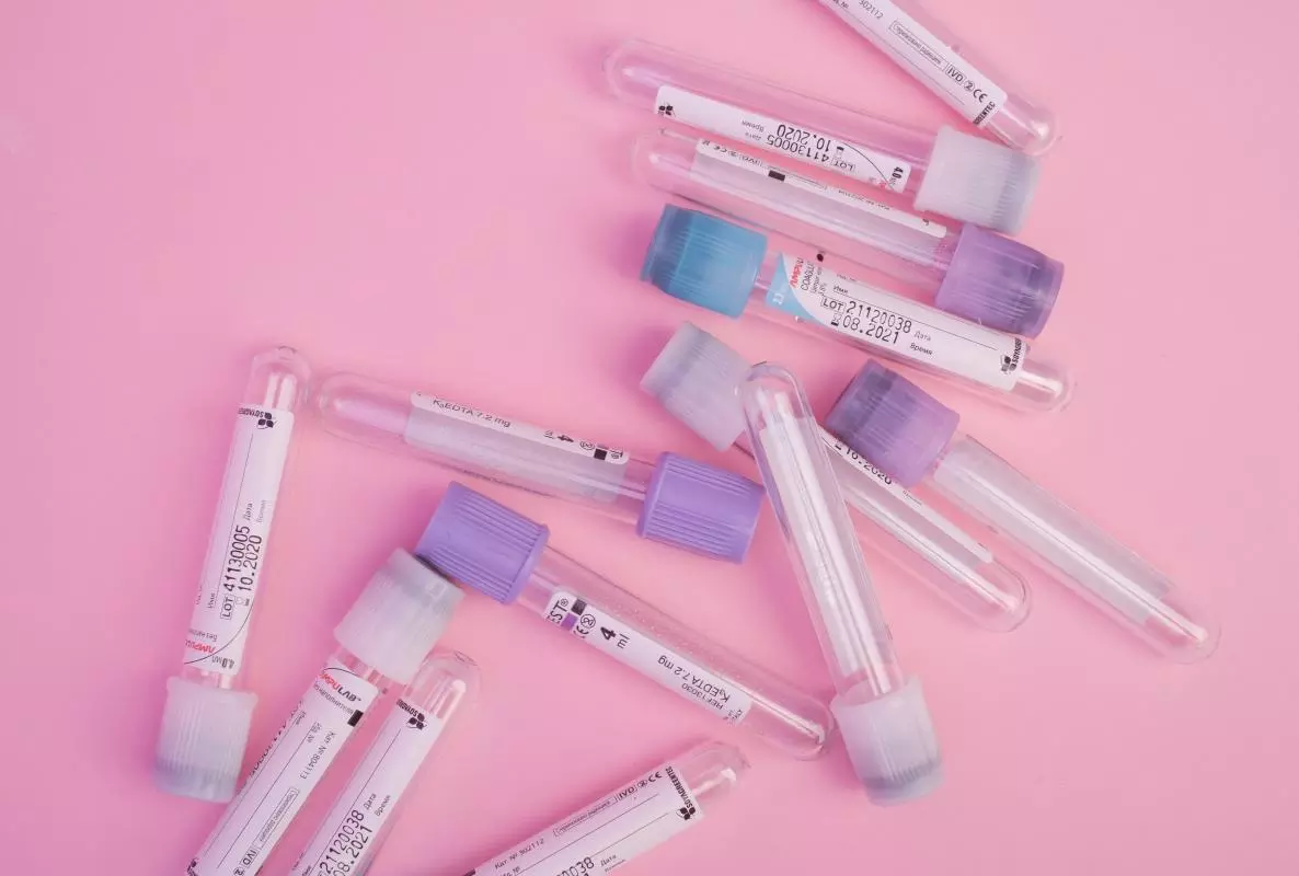 Set of blood test vials arranged on a pink table