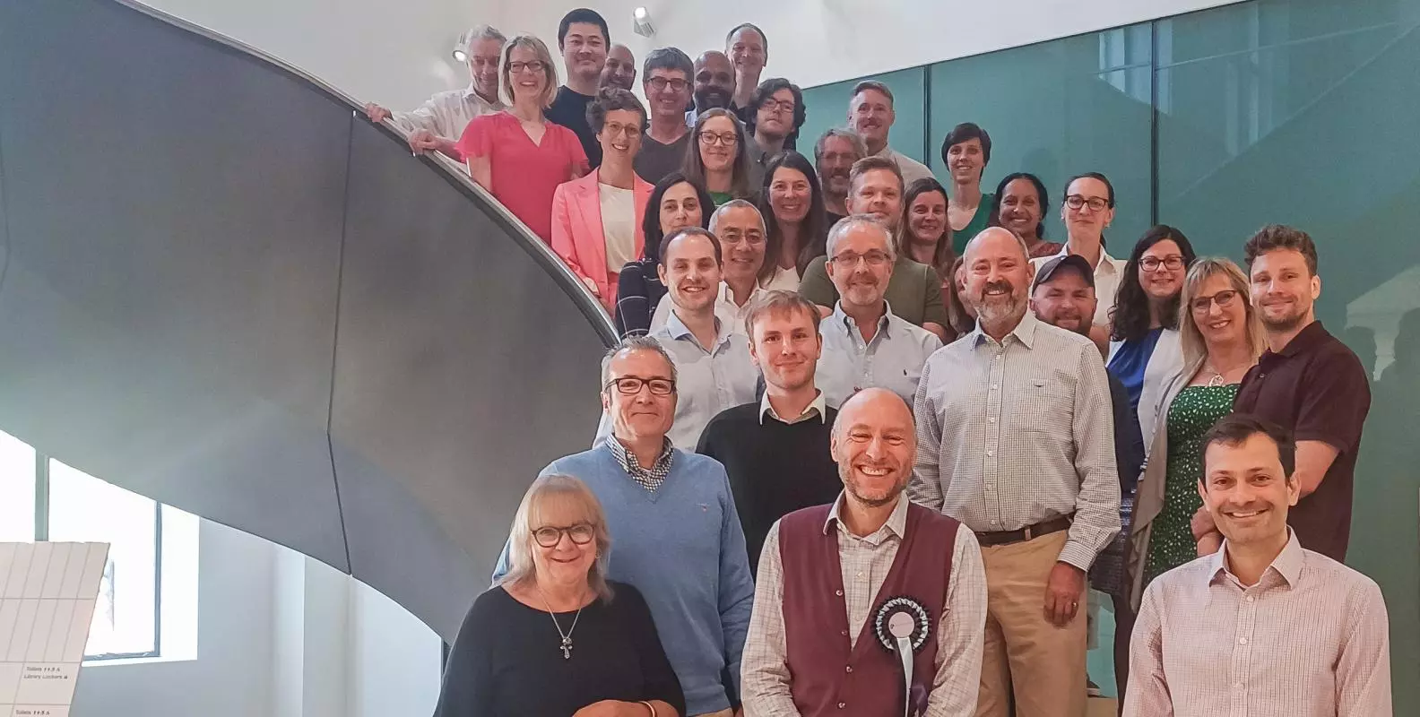 Group photo of the PAINSTORM consortium. About 25 people are standing on a large spiral staircase.